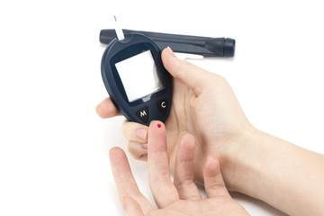 Close up of woman hands using lancet on finger to check blood sugar level by Glucose meter using as Medicine, diabetes, glycemia, health care and people concep