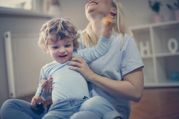 Smiling young mother playing with her baby boy.