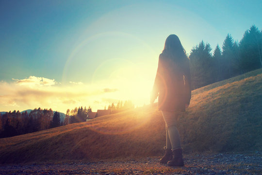 girl walking in a mountain path in sunset, silhouette of young woman in the nature (european alps)