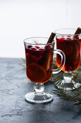 Mulled wine. Christmas hot drink with citrus, apple and spices in a glass cup on a black background.
