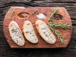 Slices of ciabatta with rosemary herb on the serving wooden tray