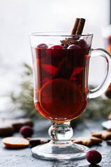 Mulled wine. Christmas hot drink with citrus, apple and spices in a glass cup on a black background.