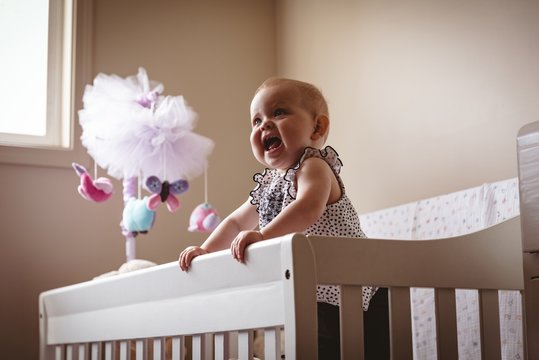 Smiling baby girl standing in crib
