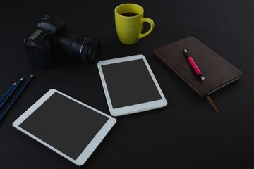 Digital tablet, black coffee, camera, organizer and pen on black