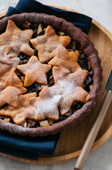 Chocolate gingerbread crust mince pie with vanilla stars on a white stone background