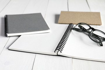 Notebook and glasses on white wooden table background.