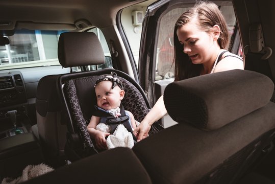 Mother adjusting stroller belt for her baby