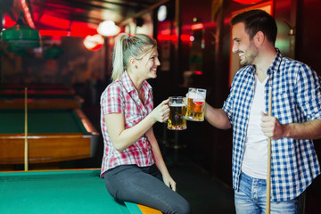 Happy couple drinking beer and playing snooker