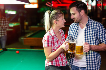 Happy couple drinking beer and playing snooker