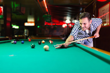 Hansome man playing pool in bar alone