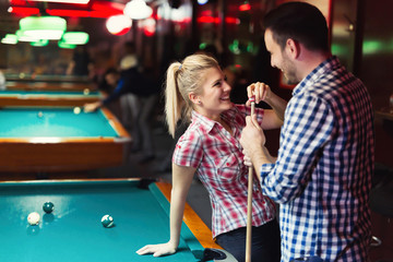 Young couple enjoying playing snooker on date