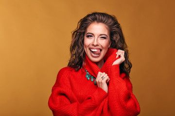 Colorful portrait of attractive brunette woman with opened mouth, wearing orange red sweater and turquoise skirt in studio with orange background