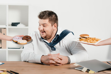 overweight businessman choosing donuts or hamburger with french fries for lunch