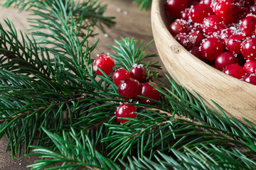 Red berries in a wooden plate on a wooden background with spruce branches. Cranberry. - 183930761
