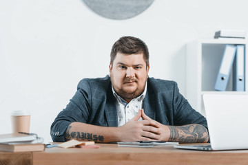 confident overweight businessman sitting at workplace in office