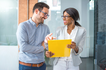 Fototapeta na wymiar Smiling business partners commenting contract while walking in office hall.