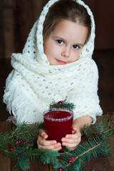 .A girl in a white knitted scarf holds a cup of cranberry mors - 183933596