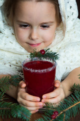 .A girl in a white knitted scarf holds a cup of cranberry mors - 183933786