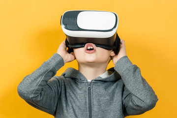 Boy with a headset of virtual reality. Innovative technology. On an orange background