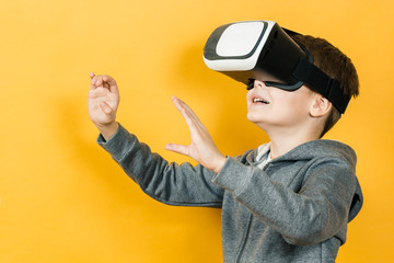 Boy with a headset of virtual reality. Innovative technology. On an orange background