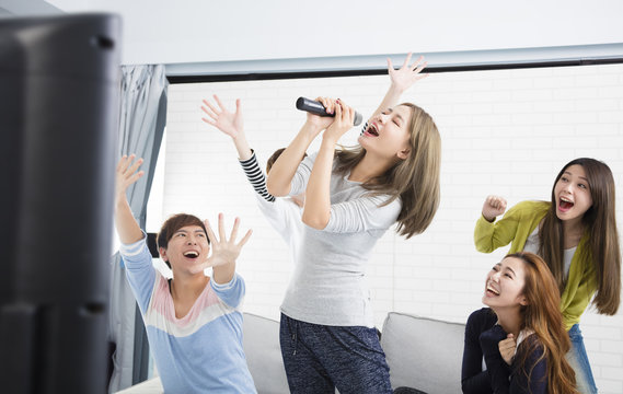 Young Woman Holding Microphone And Singing At Karaoke.