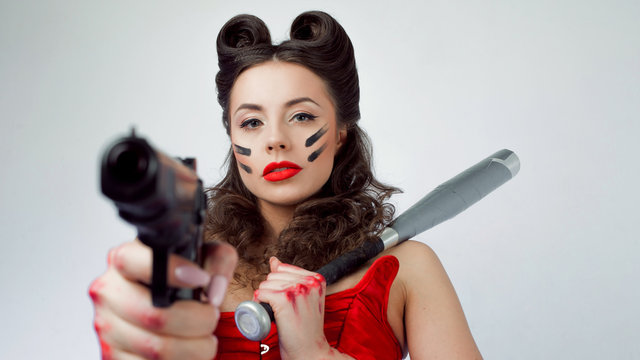 Woman in red with a gun and a bat in war paint, girl power