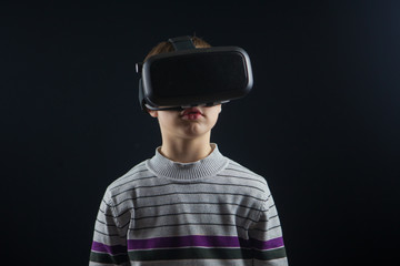 close-up boy 10 years old using a virtual reality helmet. Child getting experience in using VR 360