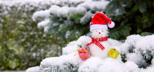 Snowman with Christmas gifts isolated on fir tree with white snow.