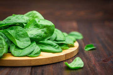 Fresh juicy spinach leaves on a wooden brown table. Natural products, greens, healthy food, vitamins.