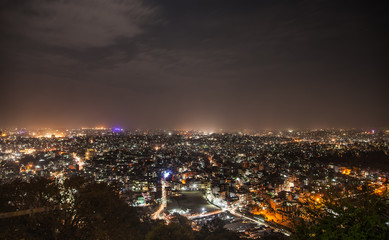 Fototapeta na wymiar Panoramic view from Svayambunath stupa point of view on old sacred city of Kathmandu in night-time beam lighting.