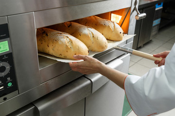 Baker gets hot bread out of the oven