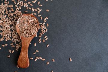 Flax seeds in spoons over dark background. Natural light. Selective focus. Close up on a black background. Top view, flat lay. copy space