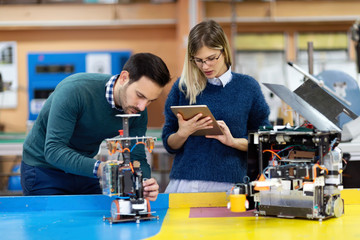 Young students of robotics preparing robot for testing