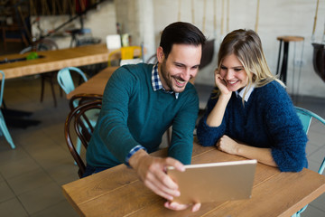 Young attractive man and beautiful woman on date looking on tablet