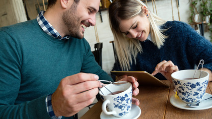 Young attractive man and beautiful woman on date looking on tablet
