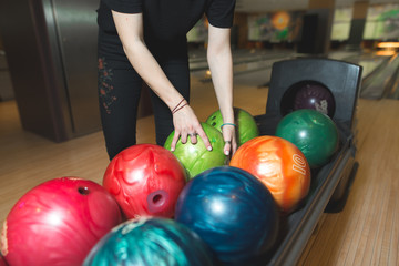 Fototapeta na wymiar Women choose a bowling ball. Choosing colored balls for bowling.