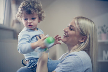 Young smiling mother playing with her baby boy.