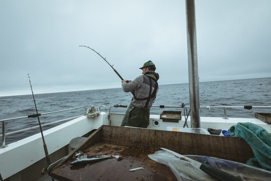 Fisherman fishing while standing on boat