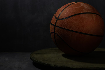 Old faded basketball on a round wooden table. Beautiful background.