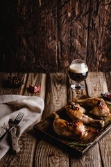 close-up shot of delicious grilled chicken legs on wooden board with glass of dark beer