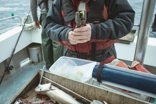 Fisherman Pressing Tag With Hand Tool