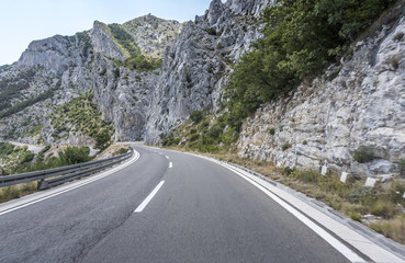 Fototapeta premium Country road through the rocky mountains and forest.