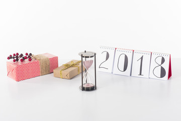 close up view of blank calendar, sand clock and wrapped gifts isolated on white