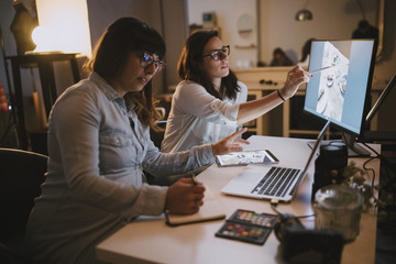 Pregnant woman working in her studio with a colleague
