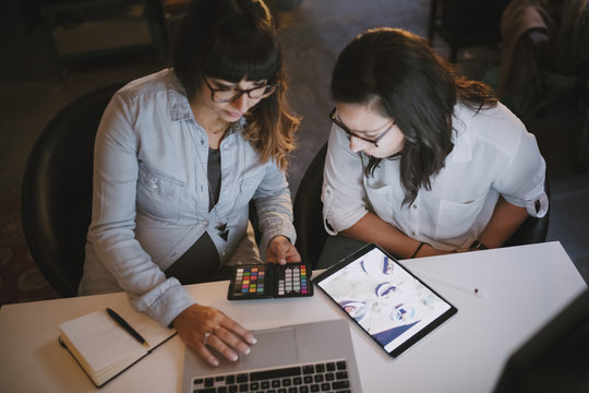 Pregnant woman working in her studio with a colleague