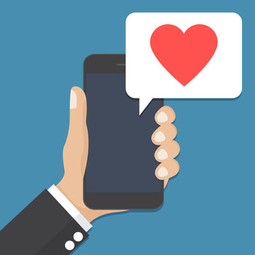 Hand holding smartphone with speech bubble and heart icon