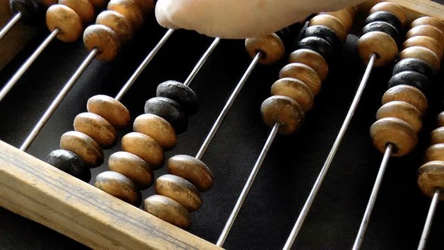 Video shows old wooden abacus. Man is making a calculation