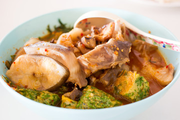 Thai Spicy Fish Soup with herbs close up.