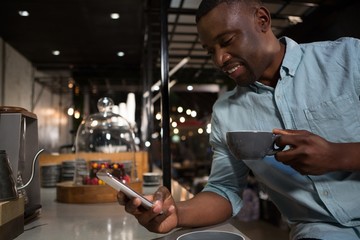 Obraz na płótnie Canvas Man using mobile phone while having coffee