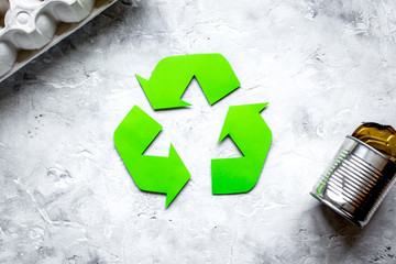 waste recycling symbol with garbage on stone background top view